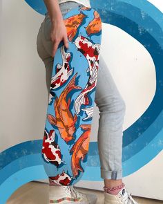 a woman standing on top of a wooden floor holding onto a fish print skateboard