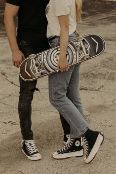 a man and woman standing next to each other holding a skateboard