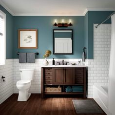 a white toilet sitting next to a sink in a bathroom under a framed mirror on a wall