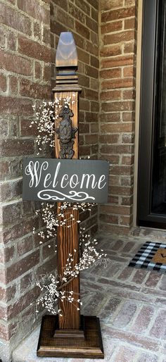 a welcome sign stands in front of a brick building with a clock on it's side