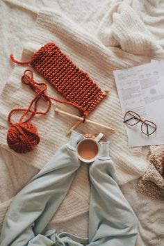 a cup of coffee and some crocheted items on a bed