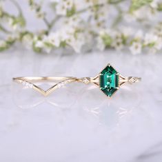 an emerald colored ring with white flowers in the background