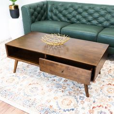 a living room with a green couch and coffee table on top of carpeted area