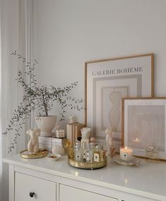 a white dresser topped with pictures and candles