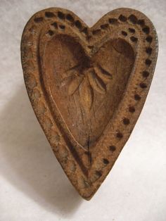 a heart shaped wooden object with holes in the middle and leaves carved on it's sides