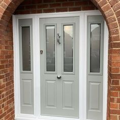 a grey double door with sidelights and glass panels on the front of a brick building