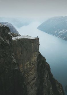 a person standing on the edge of a cliff looking out over a body of water