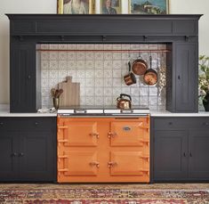 an orange stove top oven sitting inside of a kitchen next to a painting on the wall