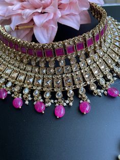 This choker is sure to be a complete statement look for your next event! made with gorgeous polki stones with antique gold finish and a pop of color with pink/purple beads, this choker is sure to be the perfect addition for your next occasion! comes with matching earrings and tikka! Pink Kundan Necklace For Reception In Temple Jewelry Style, Pink Kundan Choker For Party, Pink Choker For Party And Festivals, Pink Party Choker For Festivals, Pink Kundan Choker Necklace For Party, Pink Kundan Choker For Festivals, Pink Kundan Choker Necklace For Festive Occasions, Pink Kundan Necklace With Meenakari For Reception, Festive Pink Kundan Choker Necklace