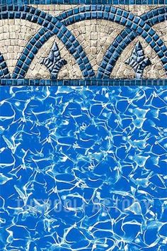 an empty swimming pool with blue water and tilework on the edge, in front of a