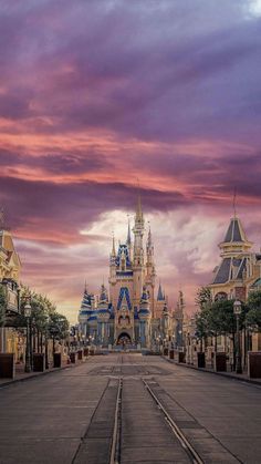 an empty street leading to a castle in the sky with clouds and trees on either side