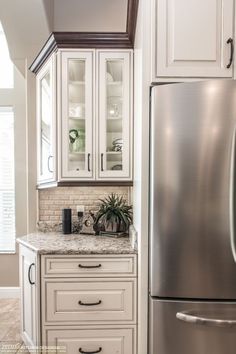 a kitchen with white cabinets and granite counter tops, along with a stainless steel refrigerator