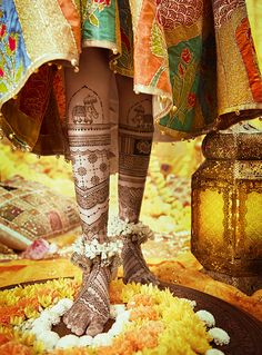 the legs and feet of a woman with henna tattoos on her body, decorated with flowers