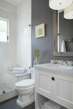 a white toilet sitting next to a sink in a bathroom under a mirror and lights