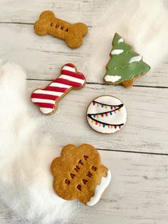 four decorated cookies sitting on top of a white wooden table next to a dog bone