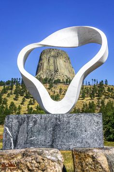 a large white sculpture sitting on top of a stone slab in front of a mountain