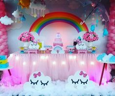 a table topped with lots of cakes and desserts next to a rainbow wallpaper