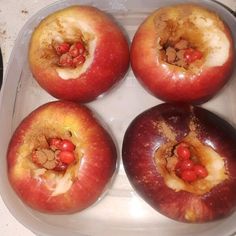 four red apples sitting on top of a white plate covered in brown stuff and sprinkles