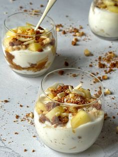 three desserts in small glass dishes with spoons on the top one is filled with fruit and nuts