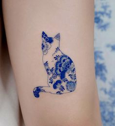 a blue and white cat tattoo on the right side of the leg, with flowers all over it