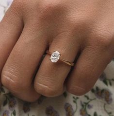 a woman's hand with a diamond ring on top of her finger and flowers