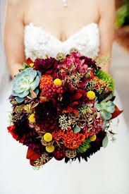 a bride holding a bouquet of flowers and succulents