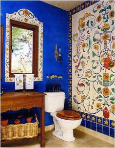 a bathroom decorated in blue and yellow with flowers on the wall next to the toilet