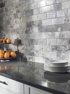 a kitchen counter with plates stacked on top of it next to a shelf filled with oranges