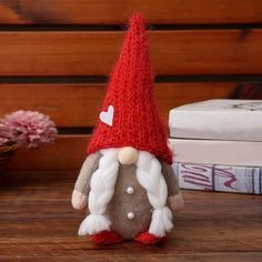 a small gnome doll sitting on top of a wooden table next to books and flowers