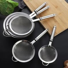 four stainless steel cooking utensils on a cutting board