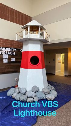 there is a red and white lighthouse in the middle of a room with blue tarp