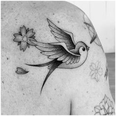 a black and white photo of a bird with flowers on it's back shoulder