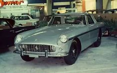 an old car parked in a garage next to other cars