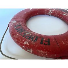 a red life preserver sitting on top of a white board next to a rope