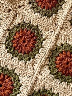 a crocheted blanket with orange and green flowers on the edges is shown in close up