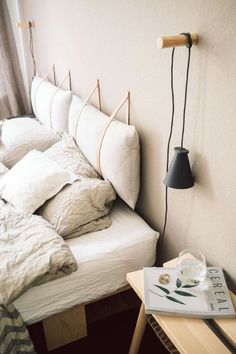 a bed with white sheets and pillows on top of it next to a wooden table