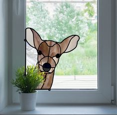 a stained glass window with a deer's head in the center and a potted plant next to it