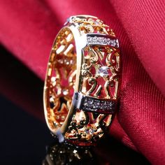 an intricately designed ring with diamonds sits on top of a red cloth in front of a black background