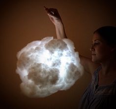 a woman standing in front of a cloud with her hand up to the clouds on it