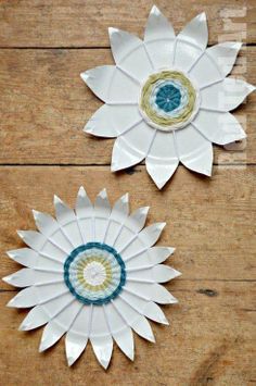 two white paper flowers sitting on top of a wooden table next to eachother