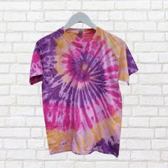 Go retro with our pink, purple and yellow tie dye t-shirt! Made from sustainable cotton and dyed with eco-reactive dyes, this pastel shirt is as environmentally conscious as it is stylish. Perfect for adding a pop of color to any outfit.  (No boring tees here!) Pastel Shirt, Yellow Tie, Shirt Tie, Yellow Ties, Tie And Dye, Environmentally Conscious, Tie Dye T Shirts, Pink Purple, Batik