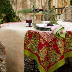 a table covered with a red and green table cloth next to a wicker basket