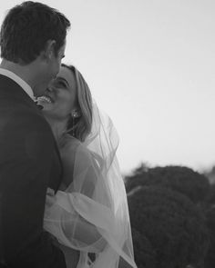 a bride and groom standing together in front of the ocean