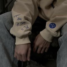 a person sitting on the ground with their hands in their pockets and writing on them