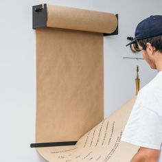 a man holding a large piece of paper next to a roll of brown paper with writing on it