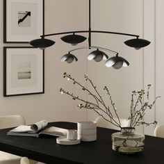 a dining room table with vases and pictures on the wall