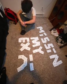 a boy sitting on the floor with letters cut out