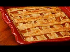 an apple pie in a red dish on a wooden table