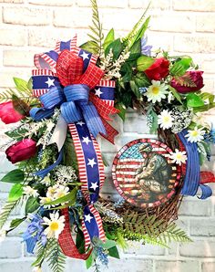 a patriotic wreath with red, white and blue flowers on the front of a brick wall