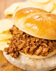 a close up of a sandwich with meat and chips on the side next to it